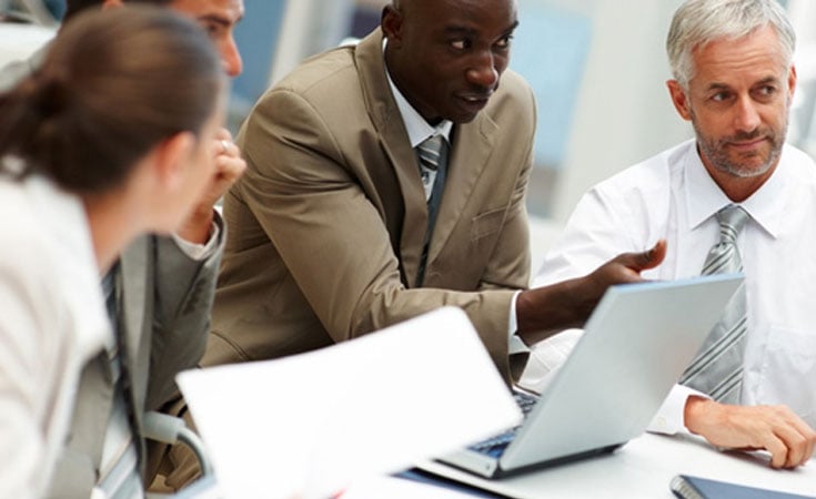 A group of business professionals debate at a meeting