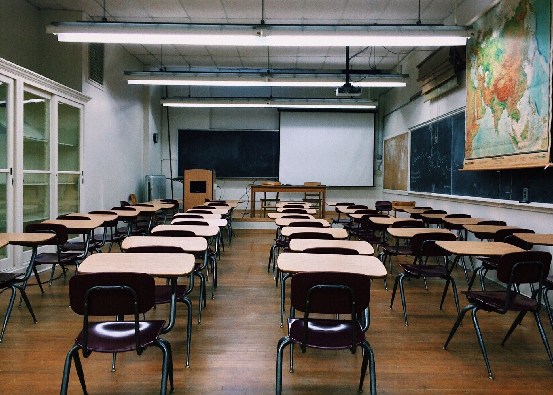 A classroom with wooden seats and a large map