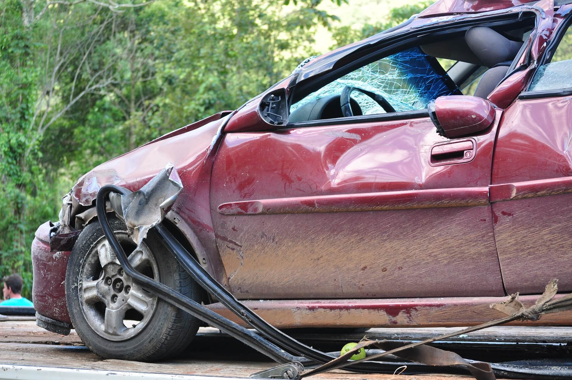 A maroon sedan is wrecked in an accident