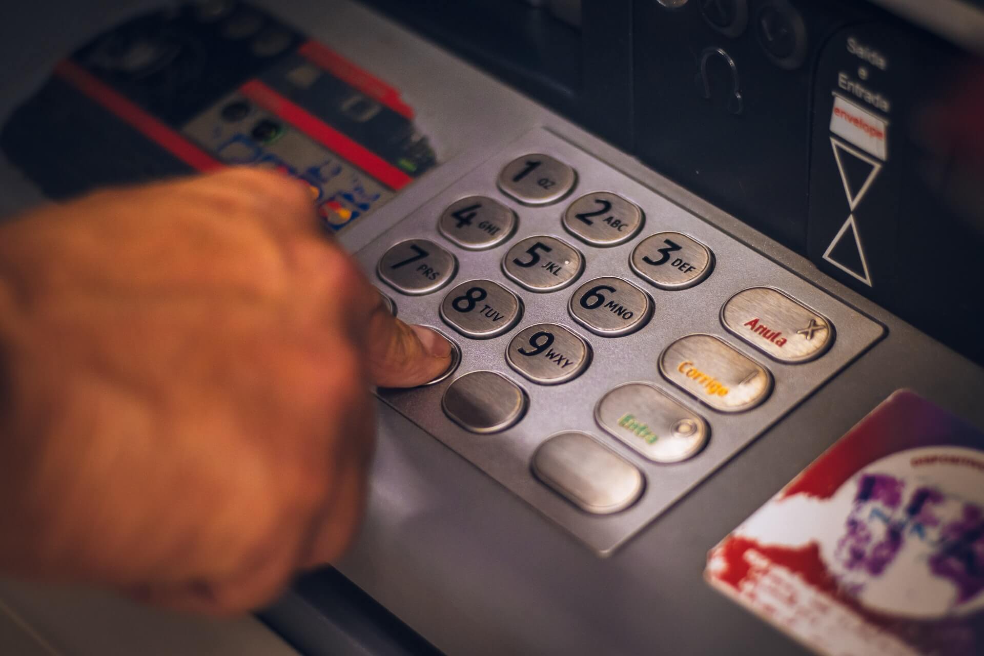 A man types in his pin at an ATM