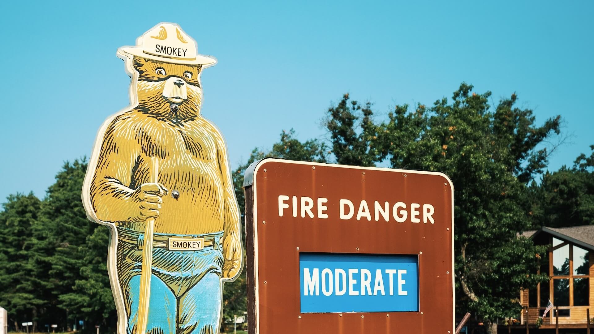 Smokey the Bear stands next to a sign that reads 