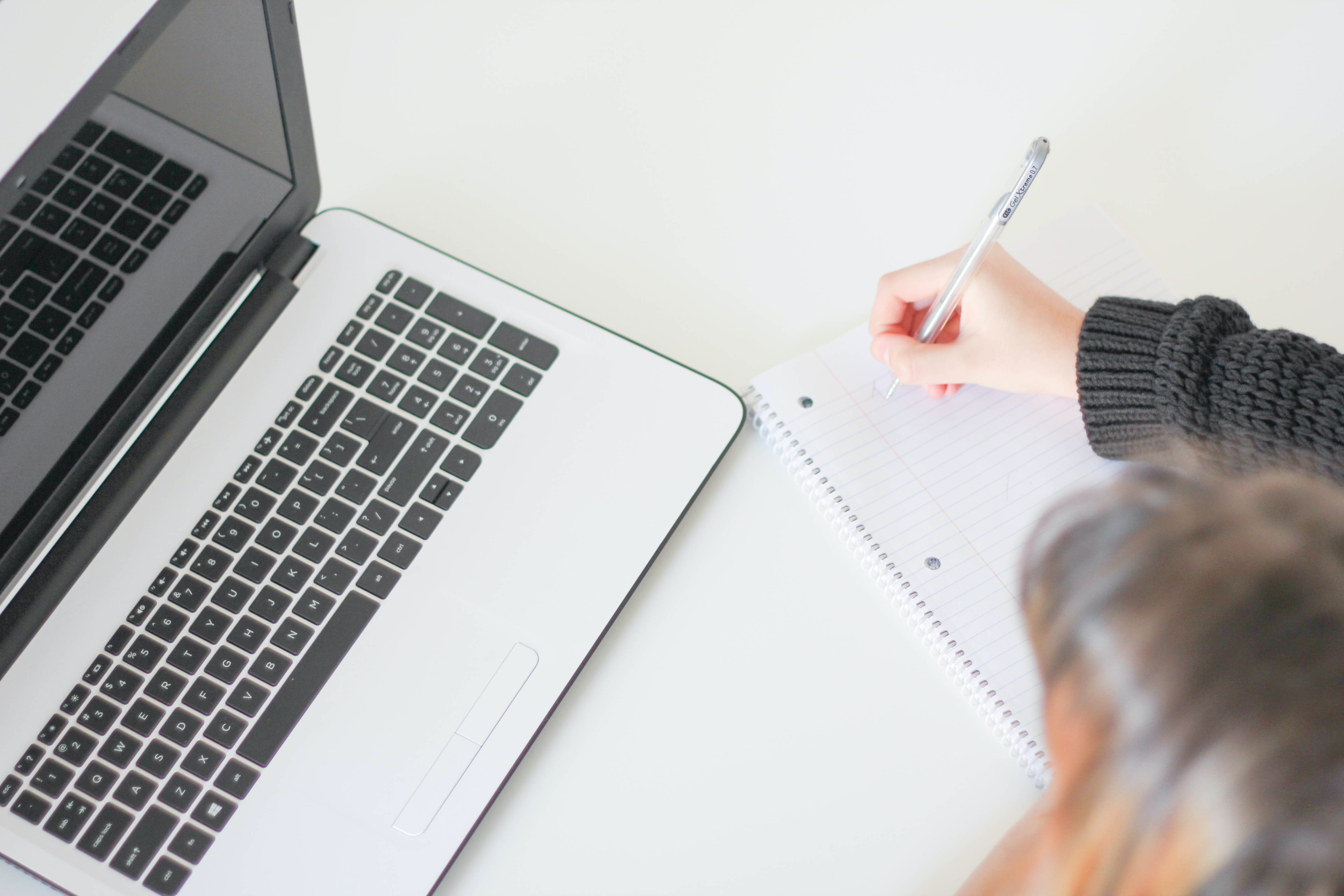 A woman takes notes next to a laptop