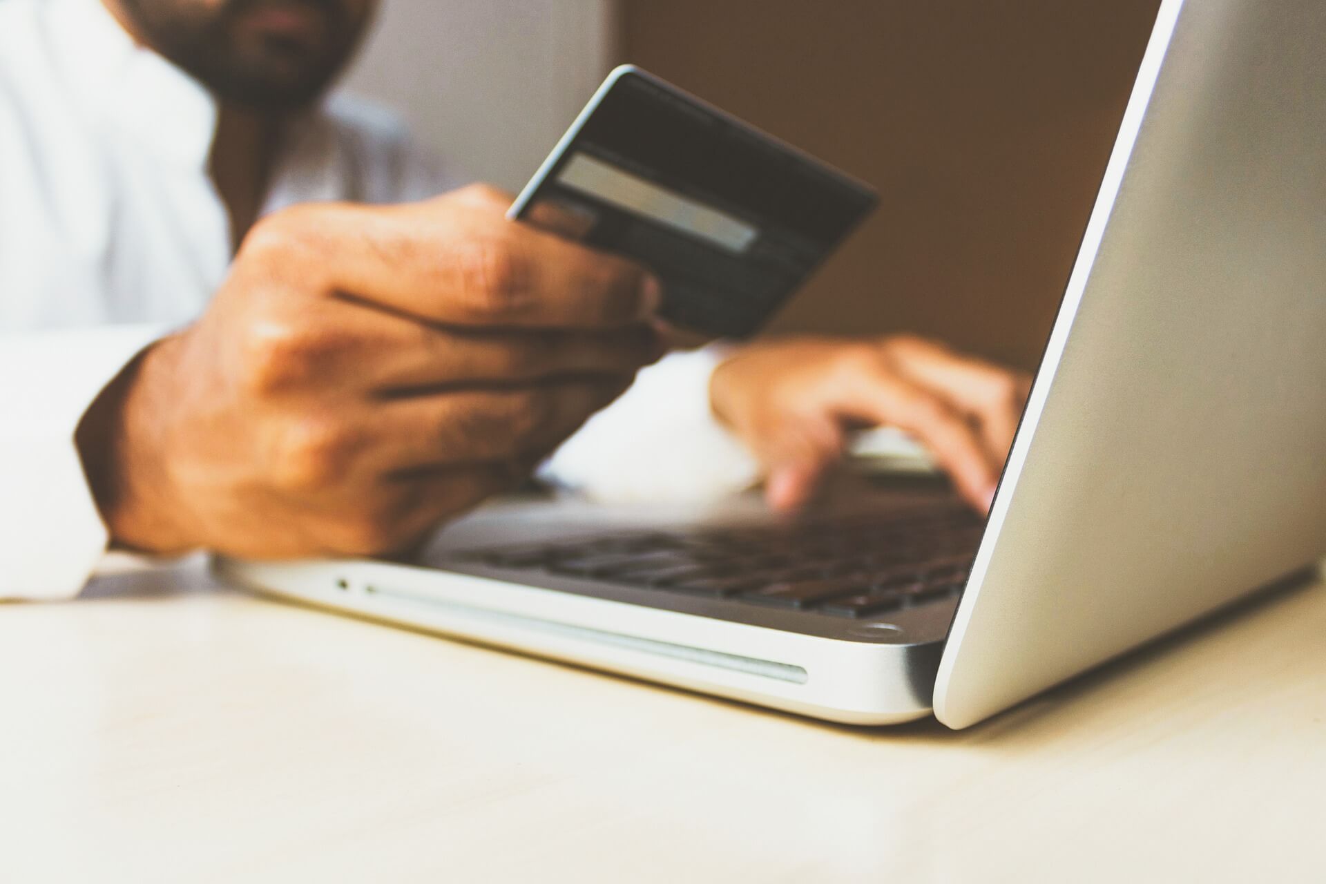 A man holds a credit card while working on a laptop